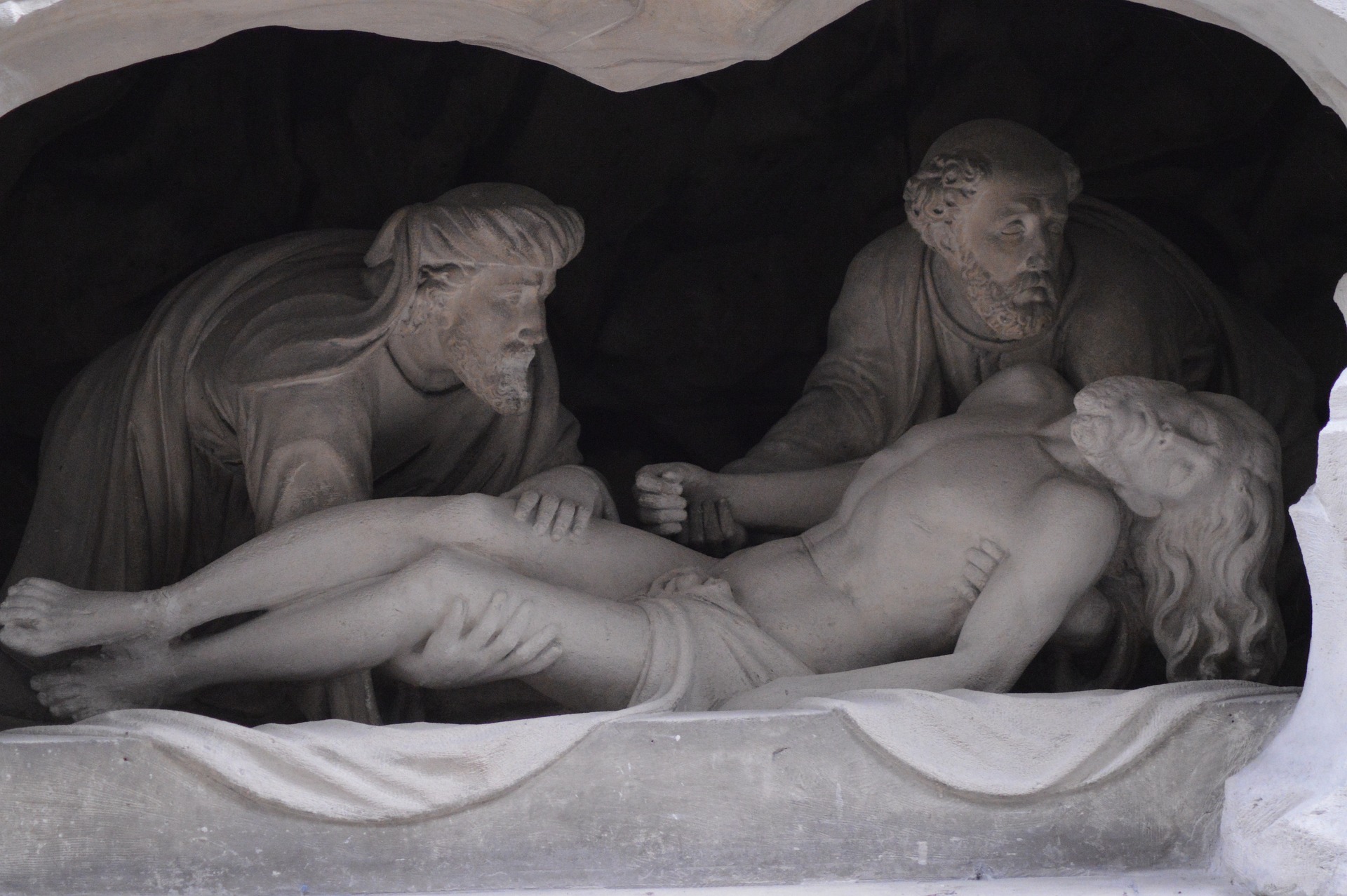 Joseph and Nicodemus wrapping Jesus in linen and placing him in the tomb.