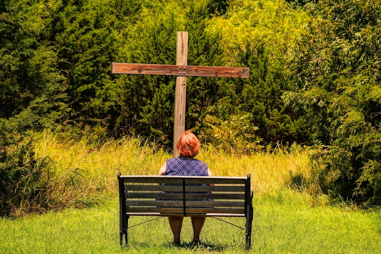A woman sitting before a cross, showing bold alignment with the suffering Savior.