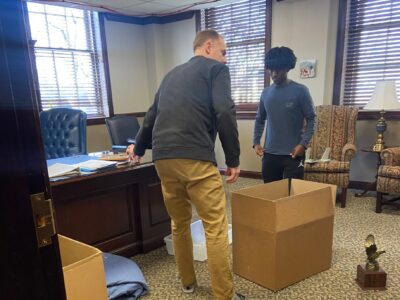 This photo shows a father and his son packing up the father's office, displaying the death of a dream.